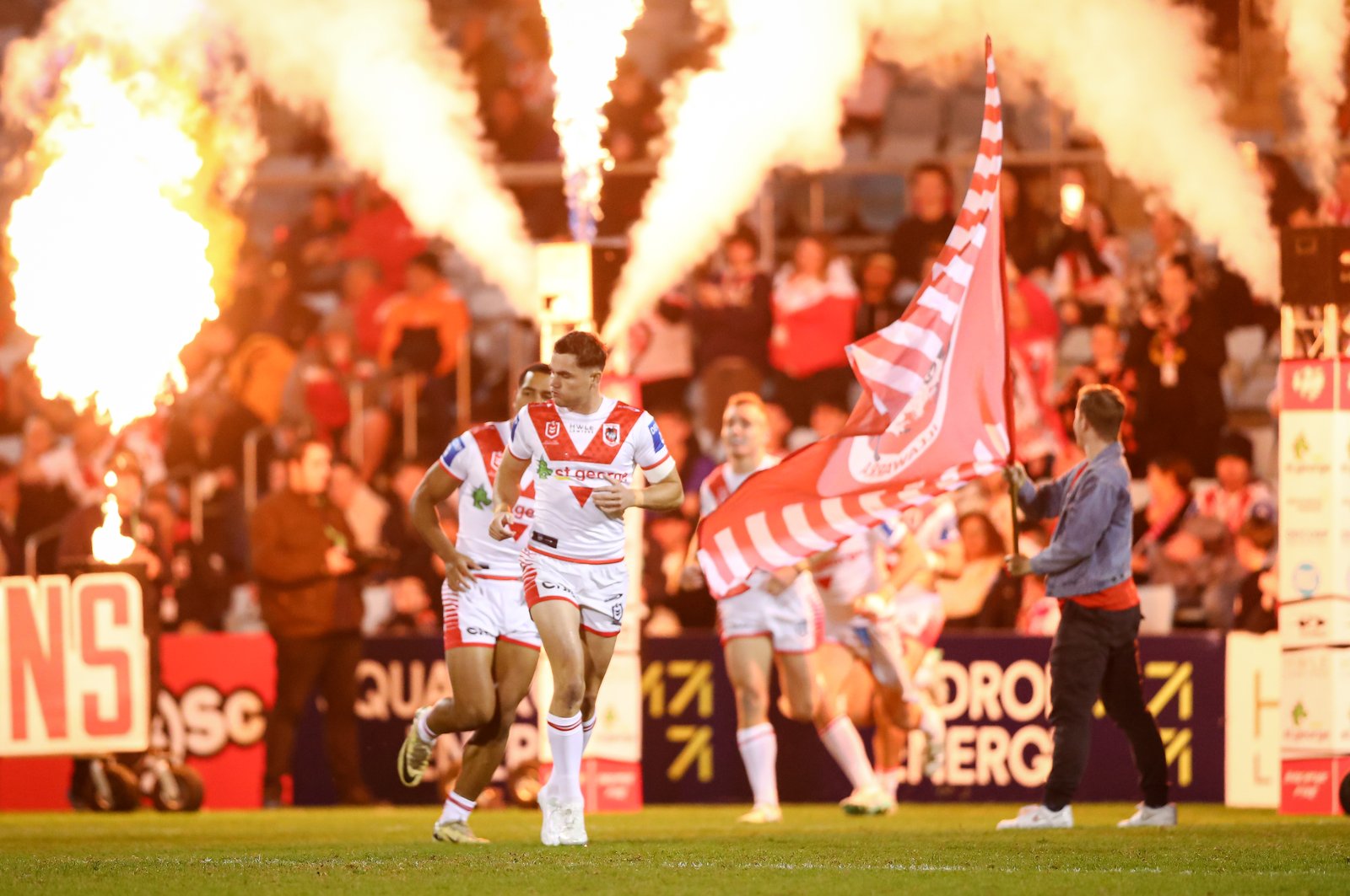 Players running onto the field through flames
